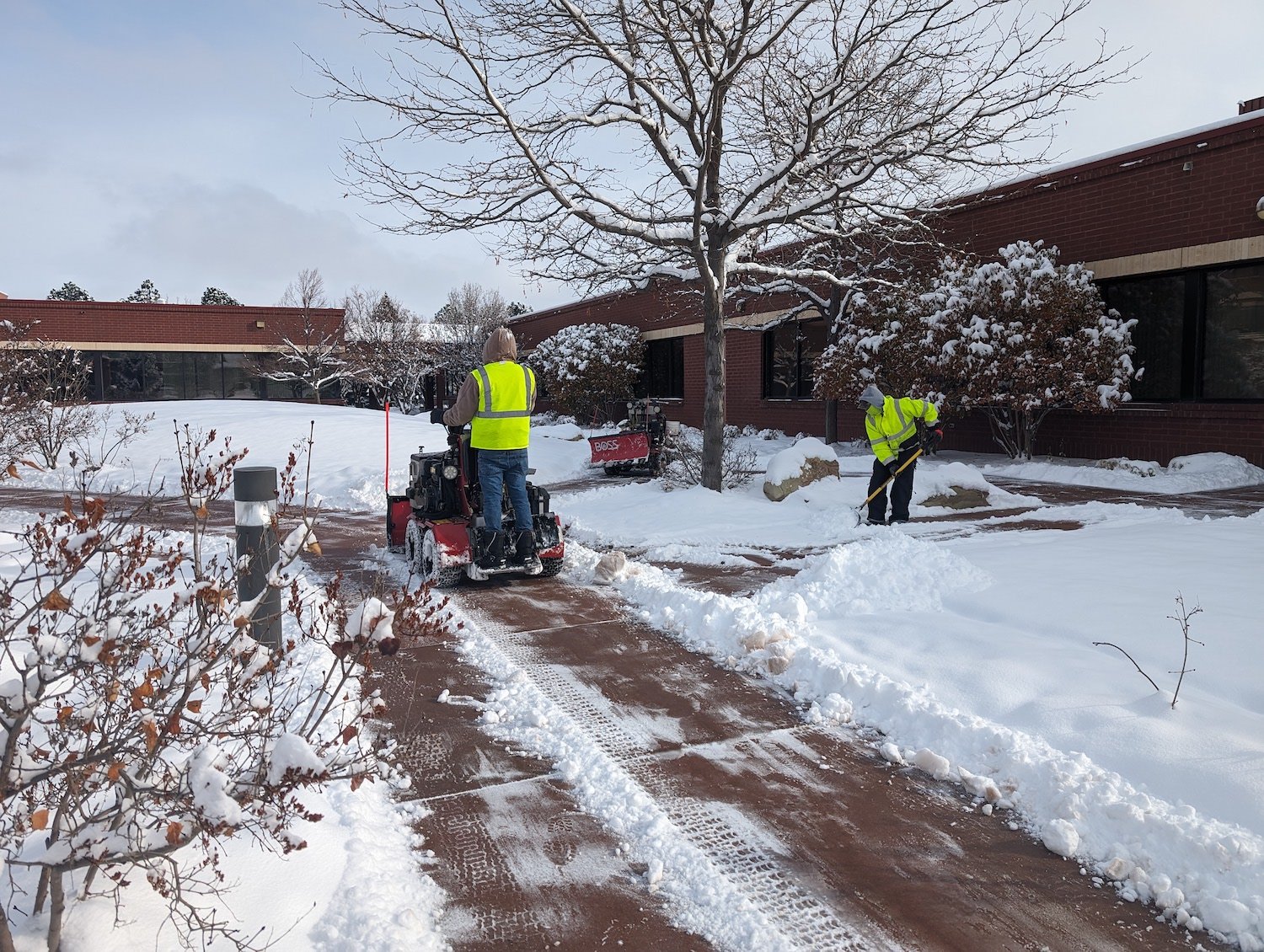 crew members removing snow by snow blowing and shoveling