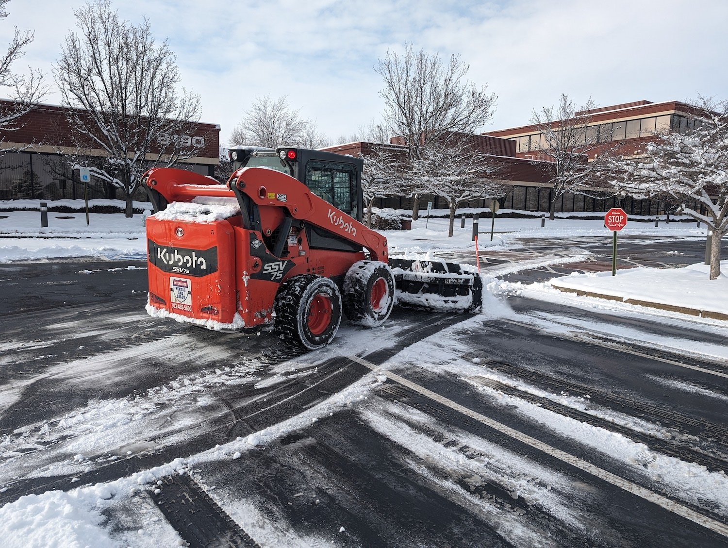 red snow plow removing snow in parking lot commercial business