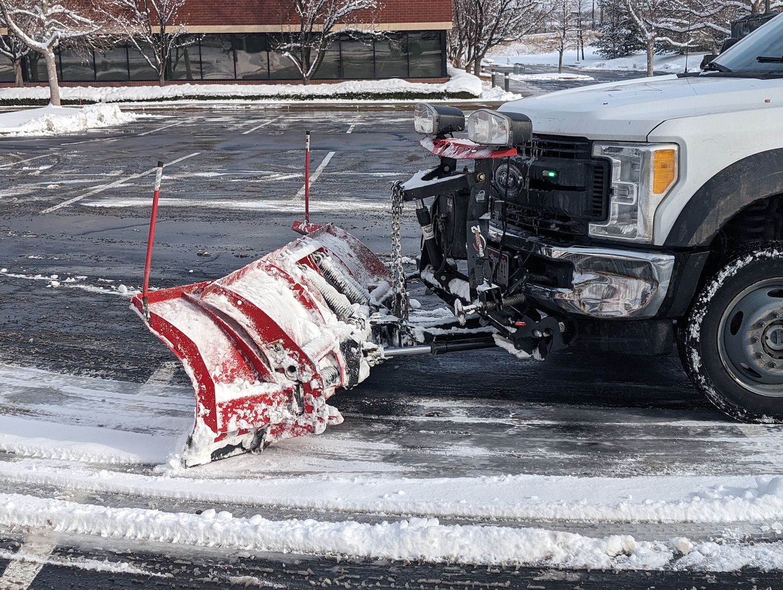 close up of snow plow removing snow from commercial business parking lot