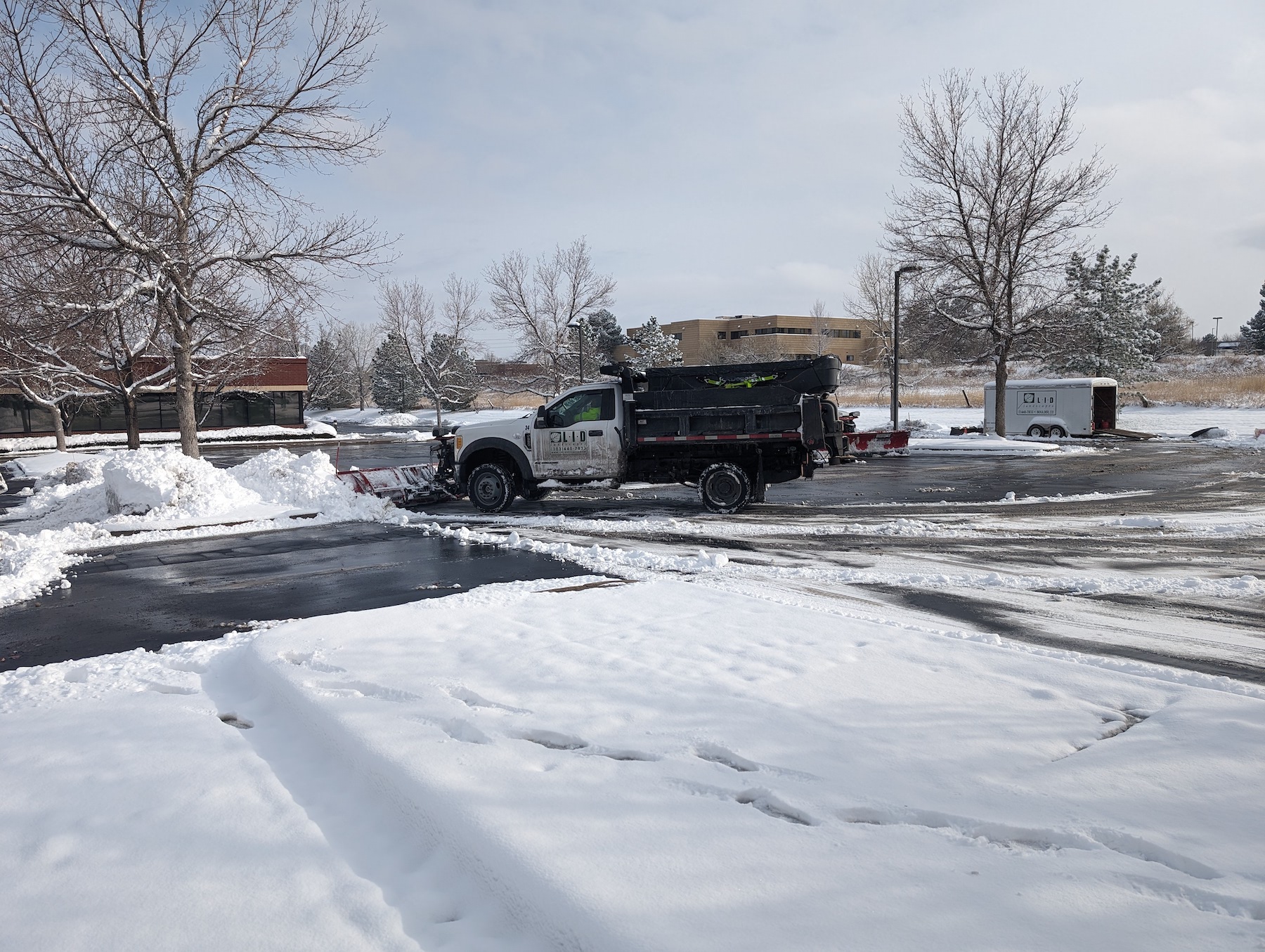 snow plow truck removing snow from parking lot putting in piles